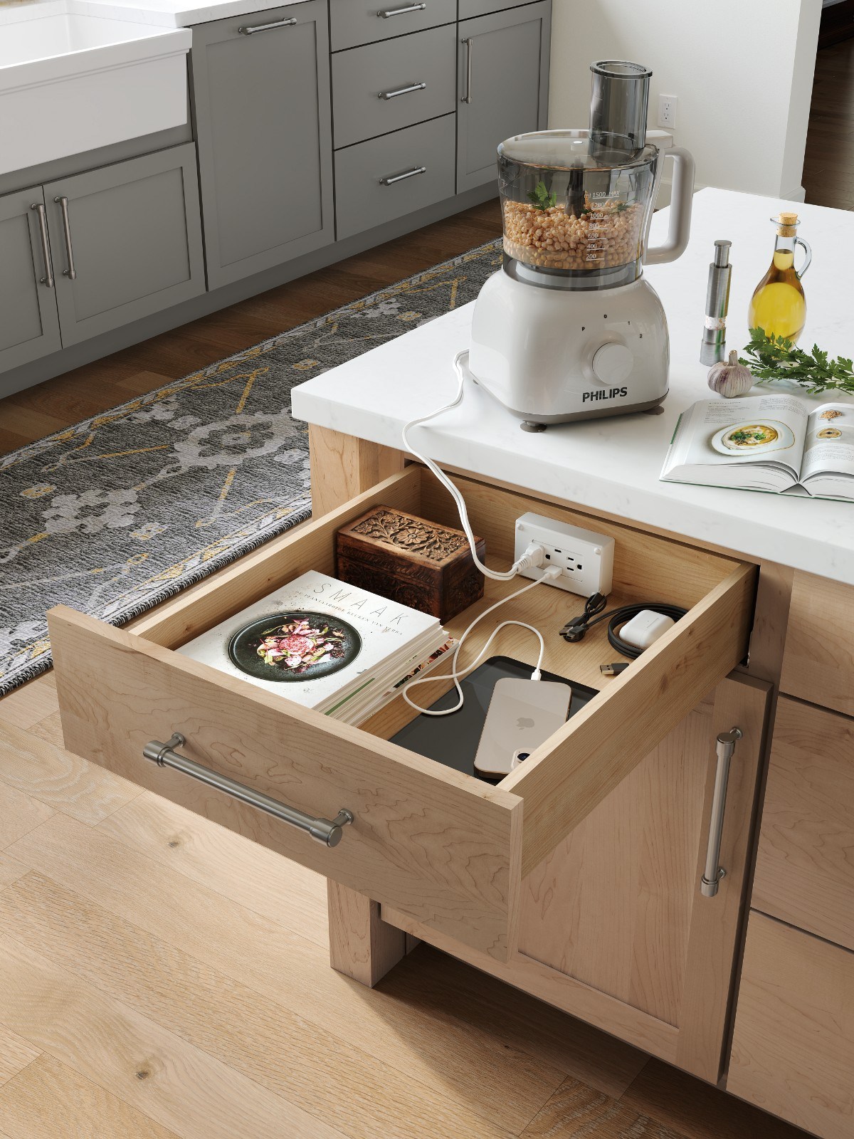 Open kitchen drawer with a built-in power outlet charging a phone and earbuds for cabinet design.