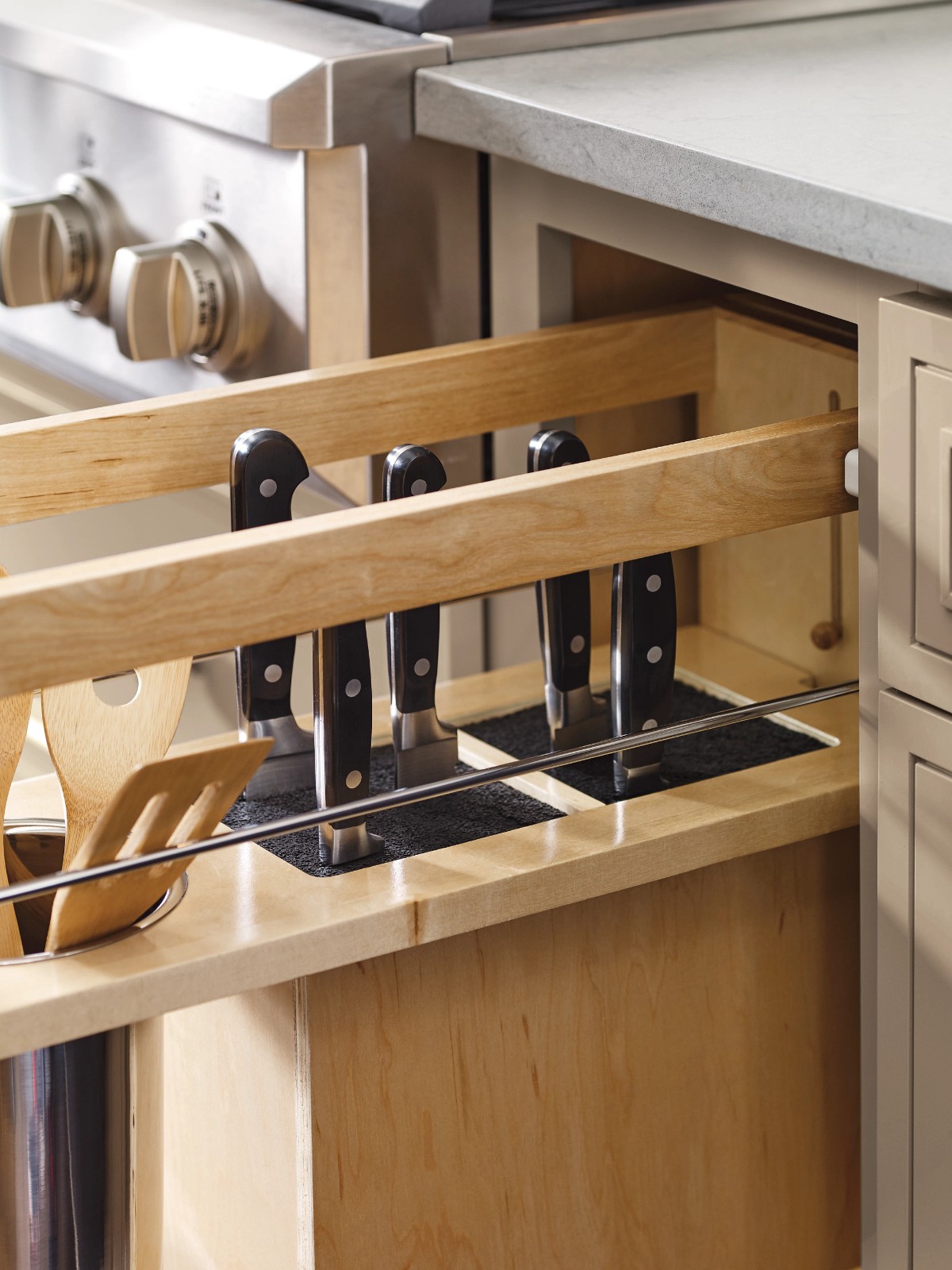 Pull-out kitchen cabinet drawer with an integrated wooden knife block and utensils.