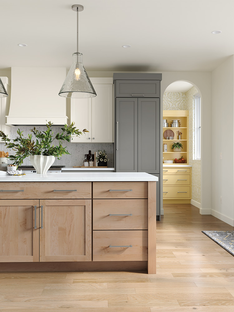 Kitchen with a light wood island, grey refrigerator, and pantry with yellow shelves.