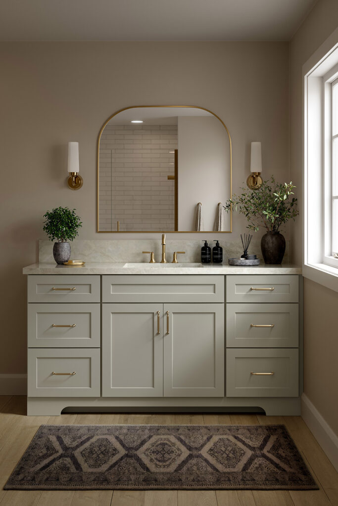 Gray bathroom cabinets with a gold-framed arch mirror, brass hardware, and two wall sconces.