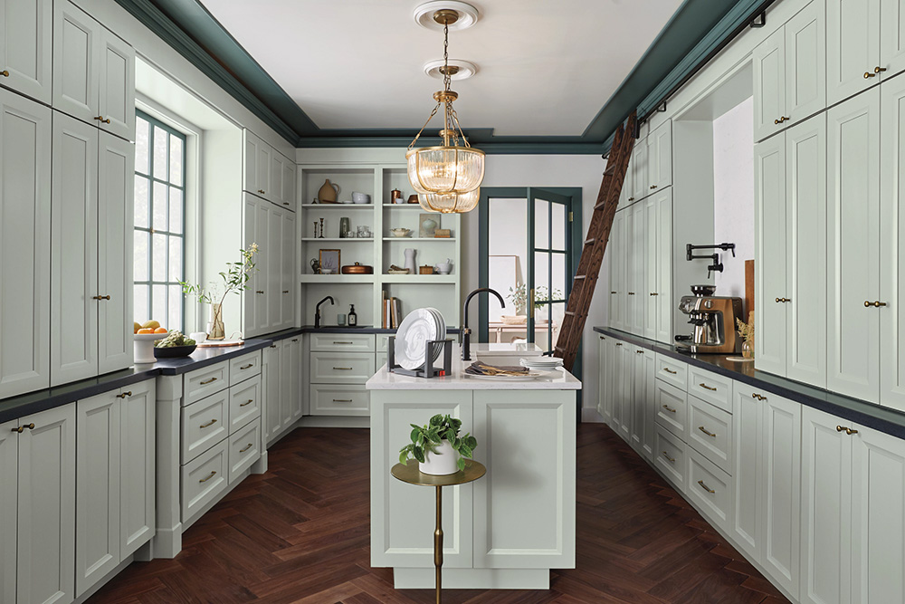A kitchen with pale green kitchen cabinets near me, a central island, and a dark herringbone floor.