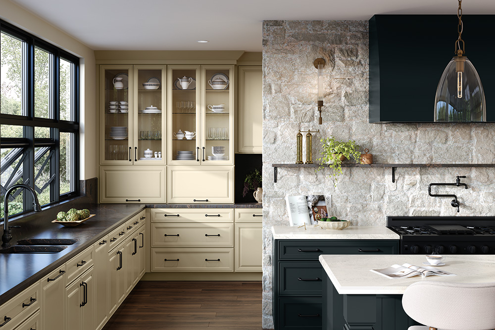 Cream glass-front hutch cabinets alongside a dark teal kitchen island set against a light stone wall with a black range hood and pot filler.