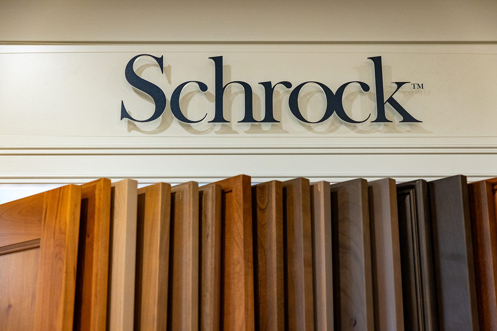 Schrock cabinetry logo sign above a row of wood finish door samples at the Bay Area Cabinet Supply showroom in the Bay Area.