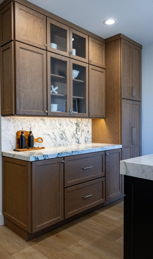 Brown wooden kitchen cabinets with marble countertops in a San Leandro, CA cabinet showroom.