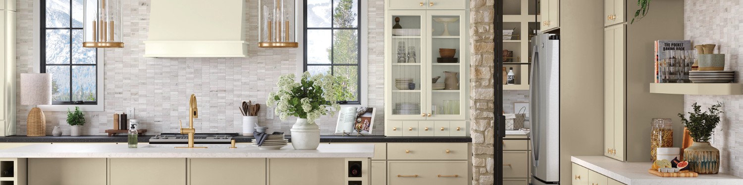 Modern kitchen with cream kitchen cabinets, gold hardware, and a stone backsplash.