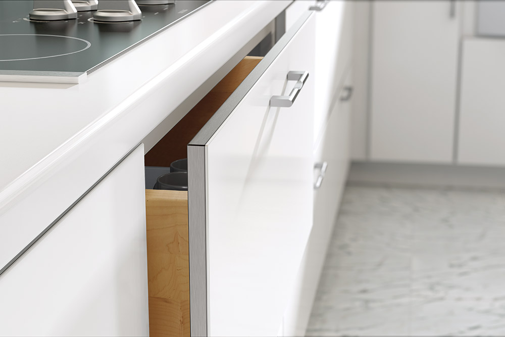 A white kitchen drawer pulled slightly open, revealing a wooden interior for cabinet inspiration.